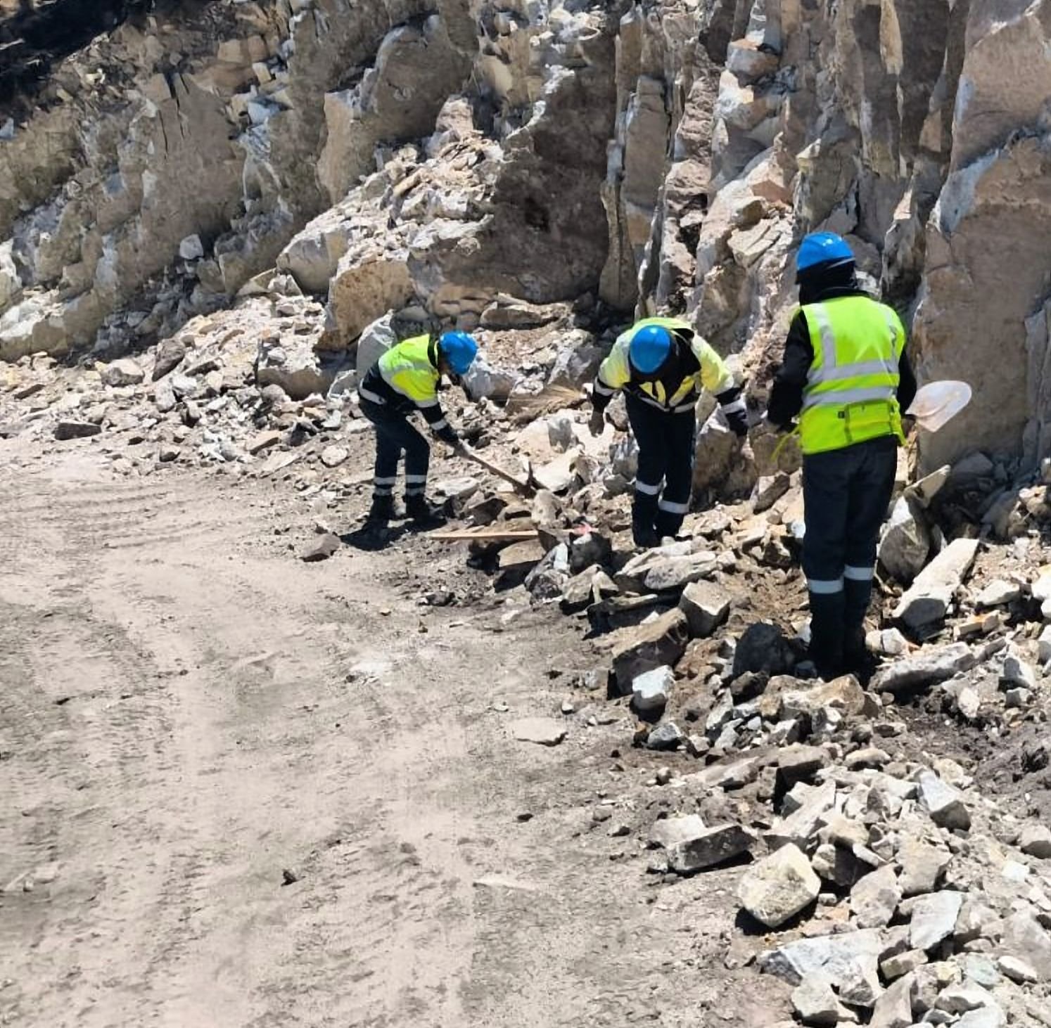 Cuadrilla mejorando la cuneta de un acceso junto a un talud de roca