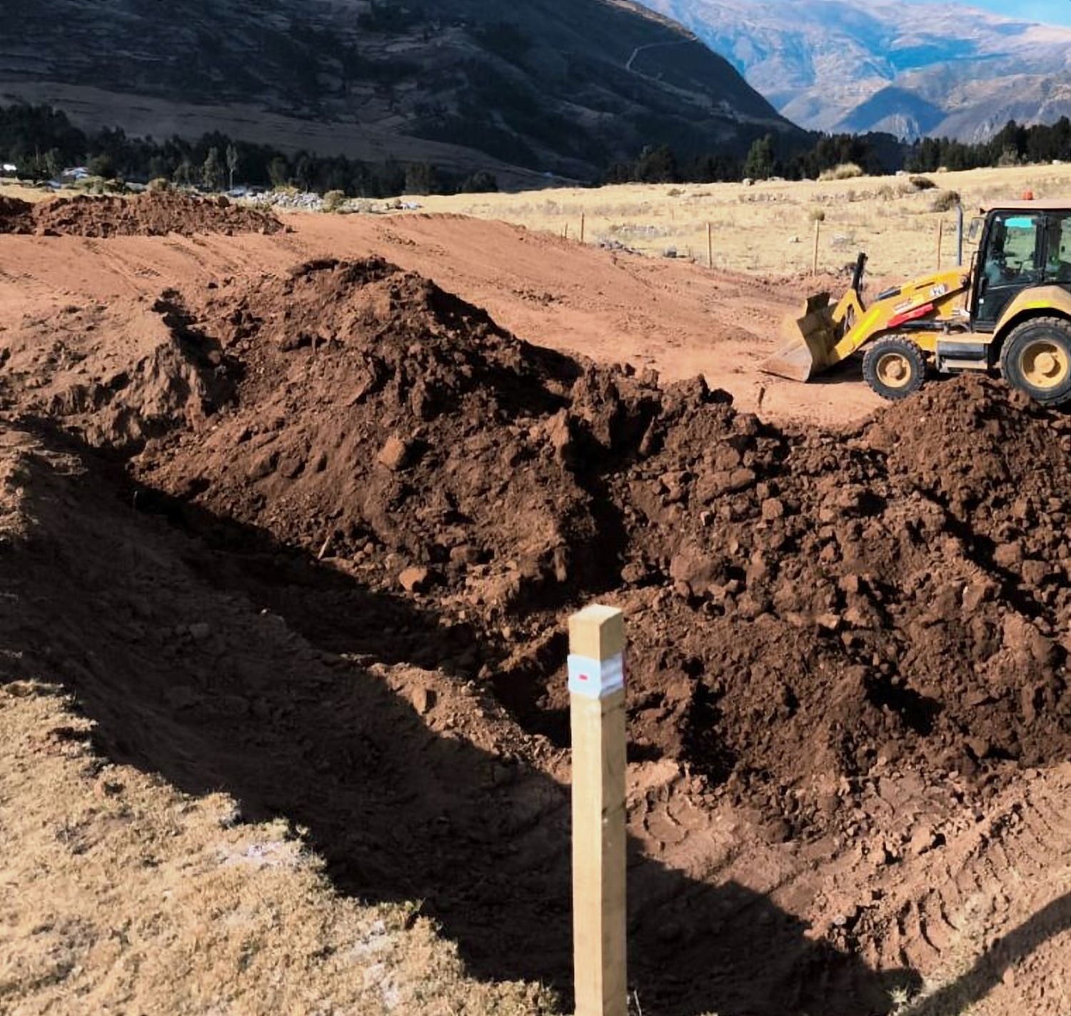 Retroexcavadora excavando una plataforma en tierra roja