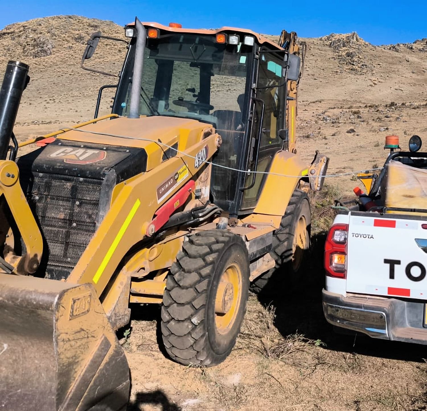 Retroexcavadora y camioneta de apoyo en un frente de trabajo