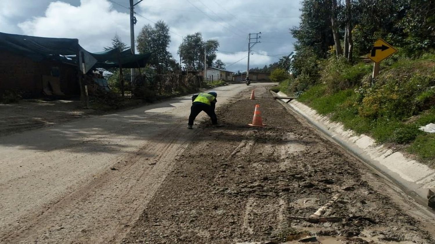 Trabajador limpia la berma de la vía junto a la cuneta de concreto terminada