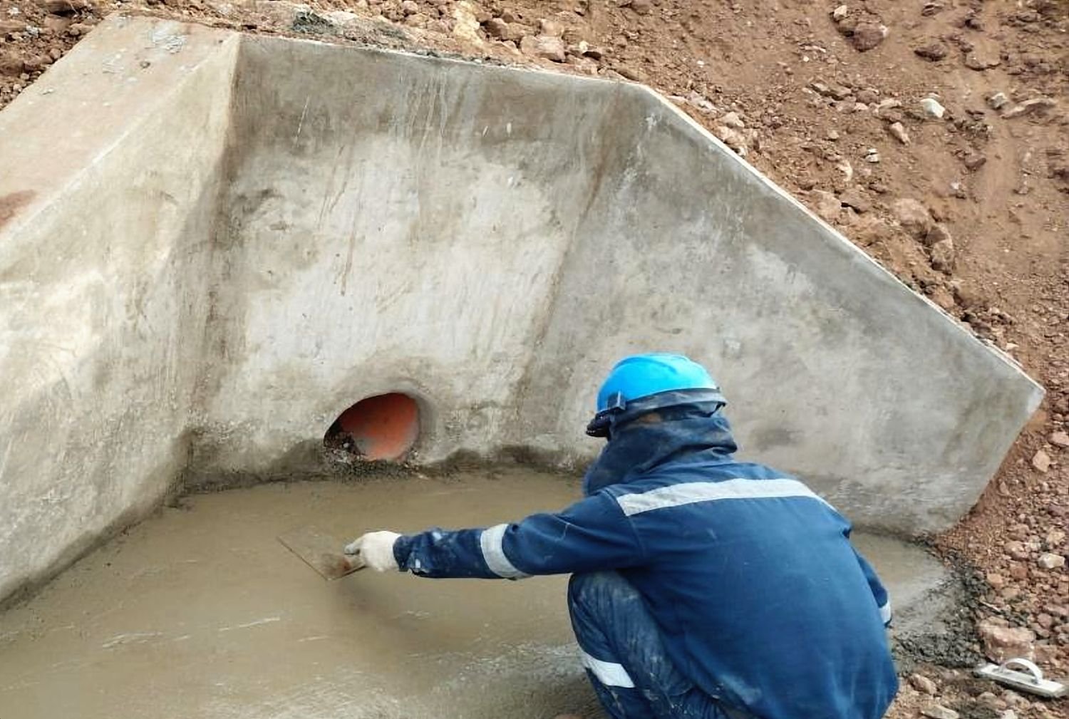 Trabajador da el acabado al cabezal de concreto de una alcantarilla